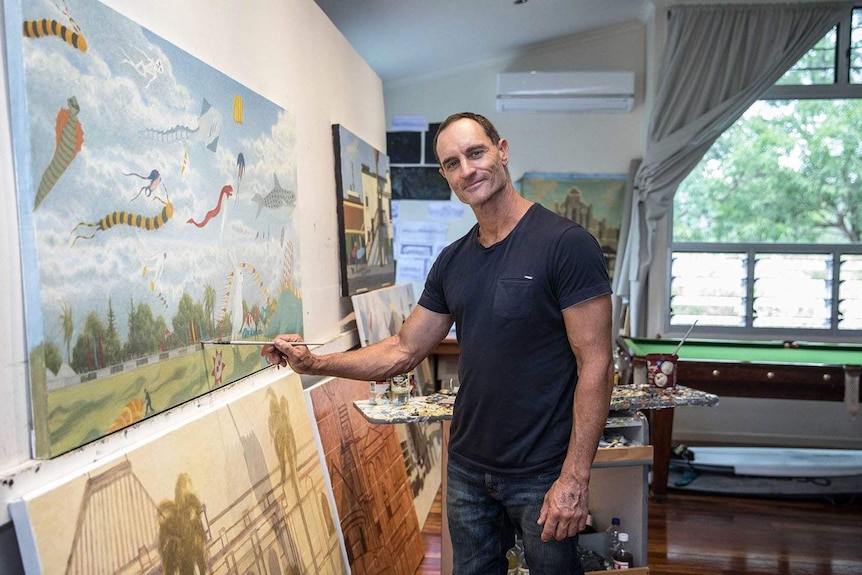 Acclaimed Australian artist Robert Brownhall stands alongside some of his paintings in his studio in Brisbane.