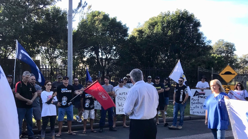 Union members form a picket line with flags at the Port Kembla Coal Terminal.