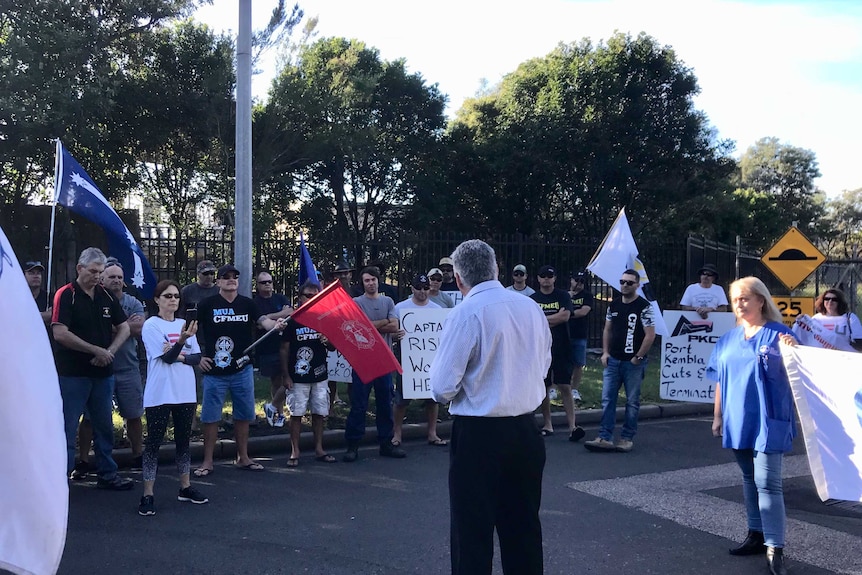 Union members form a picket line with flags at the Port Kembla Coal Terminal.