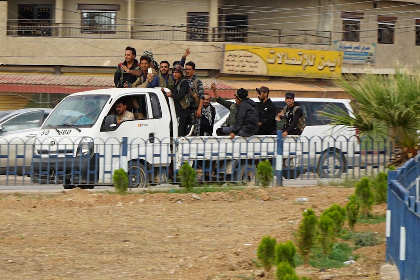 Soldiers aligned with the Assad regime drive around town on the back of trucks.