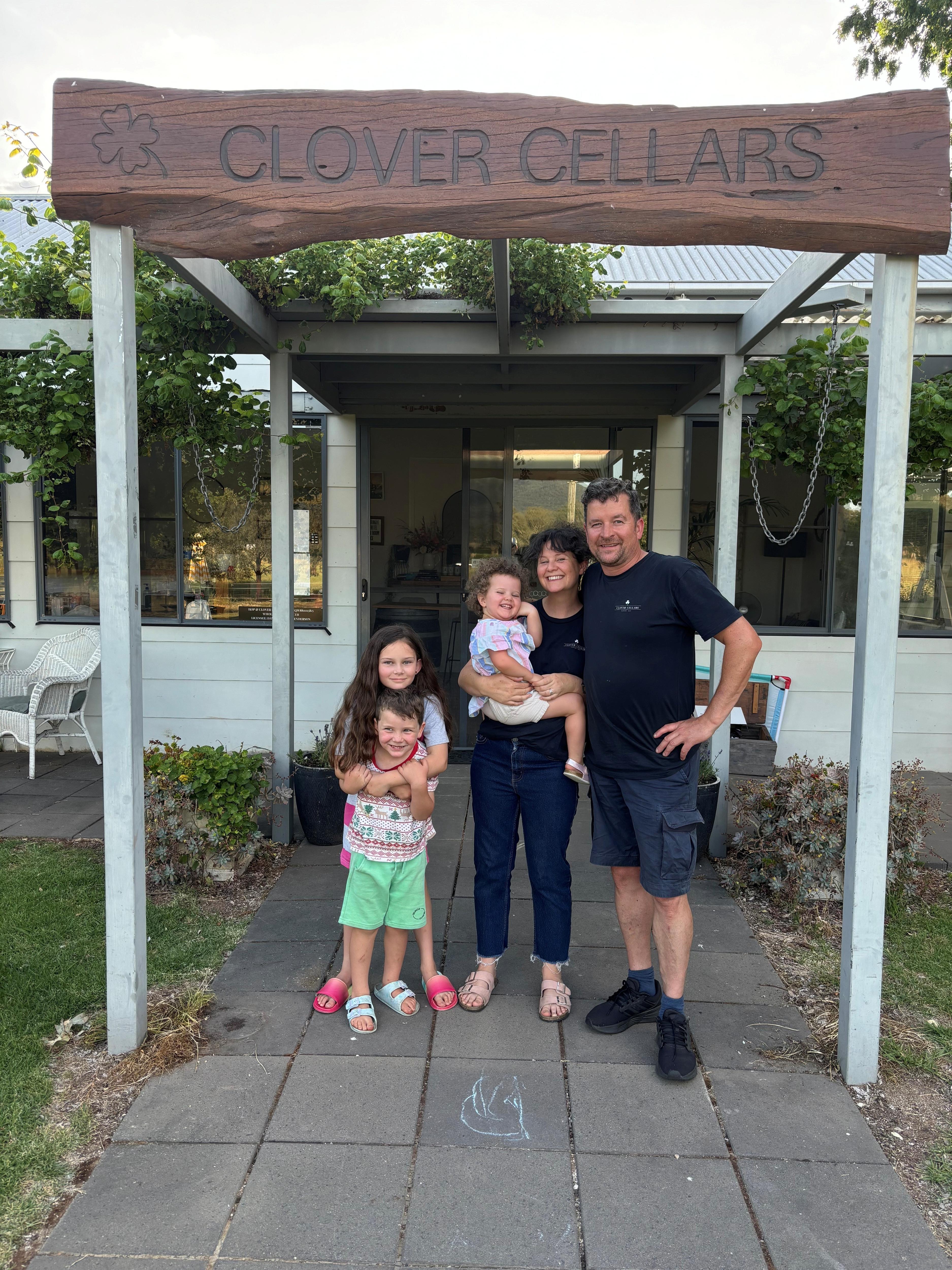 Un hombre y una mujer con tres niños pequeños se encuentran frente a una casa.