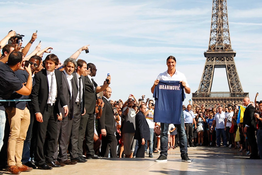 Sweden's Zlatan Ibrahimovic holds his new Paris Saint-Germain jersey in front of the Eiffel Tower.