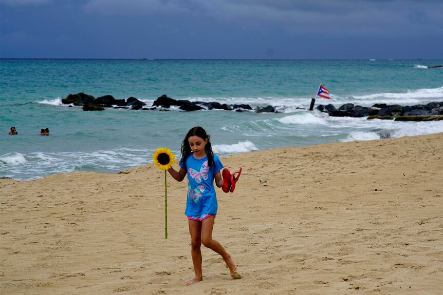 A girl walks on a beach in Puerto Rico as a storm looms in the background