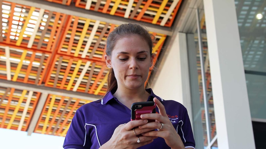 Researcher Liana Varrone looking at her phone at Darwin's Menzies School of Health building.