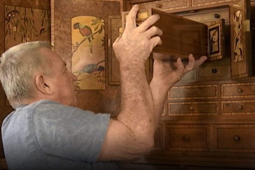 A man reaches into a cabinet revealing drawers within drawers.