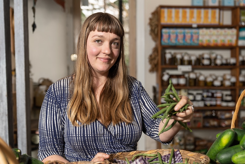 Jacinta Carmichael-Parissi holding a handful of beans inside a produce store.