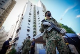 Armed soldiers stand outside a tall apartment building in Malaysia