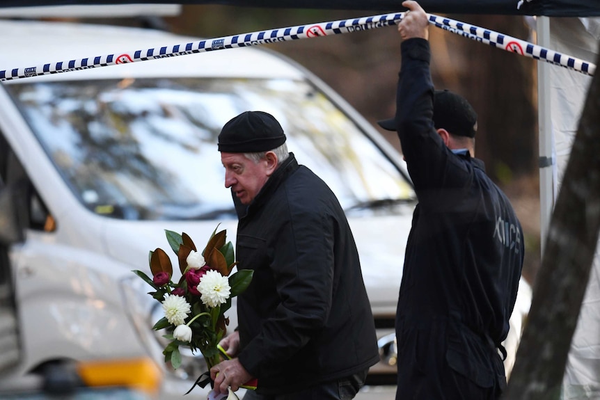 Police lifting up police tape to let Mark Leveson.