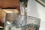 Water flowing out of a tap into a glass.