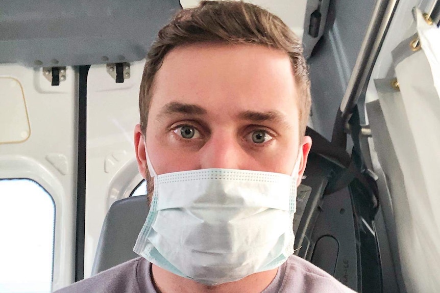 A man wears a face mask in an ambulance.