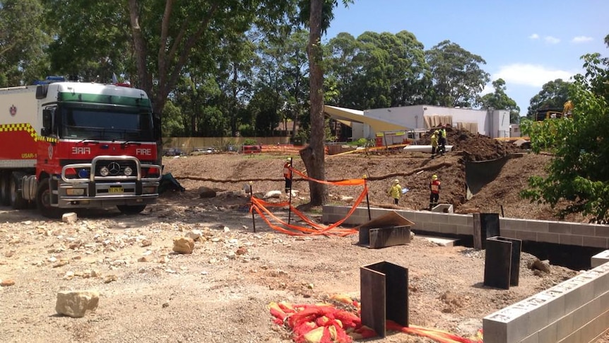 Rescue workers try to free a man killed in a trench at Cherrybrook