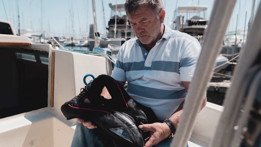 Mike Walker holding a life jacket while sitting on a yacht.