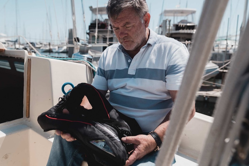 Mike Walker holding a life jacket while sitting on a yacht.