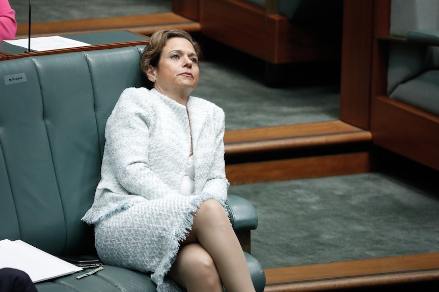 Rowland looks bored, leaning back in her seat in Parliament.