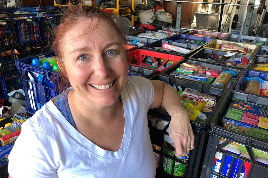 Woman in front of many rows of milk crates filled with donated groceries.