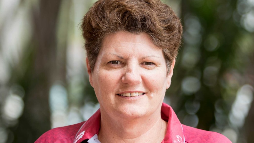 A woman stands outside, smiling at the camera.