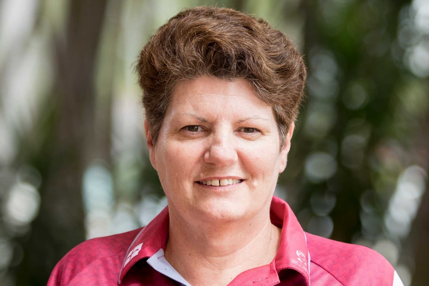 A woman stands outside, smiling at the camera.