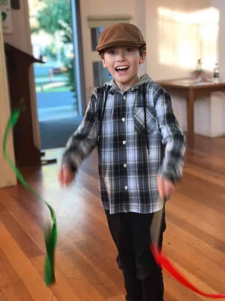 An eight-year-old boy dancing in his home.