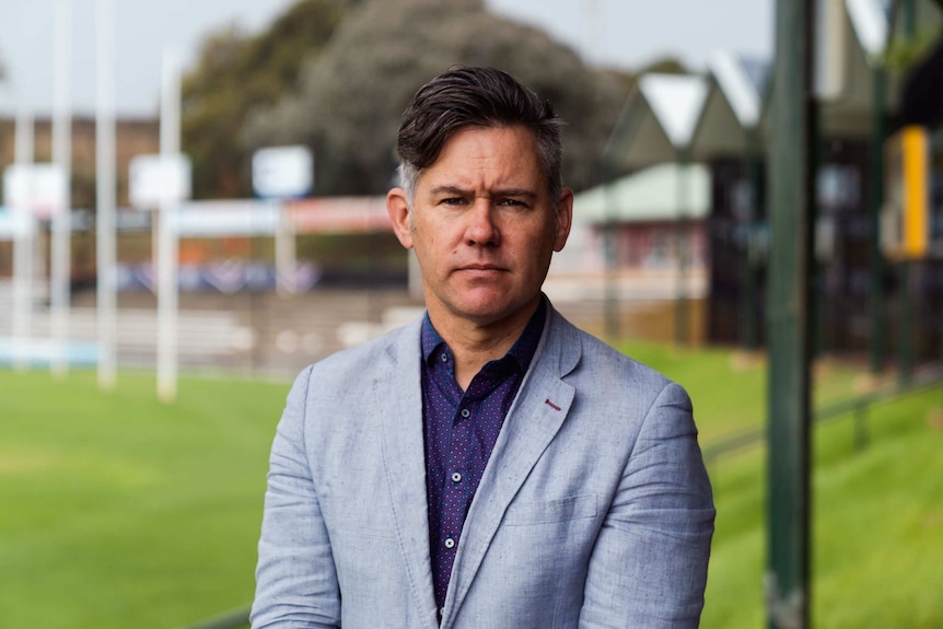 Man in suit stands in empty football stadium