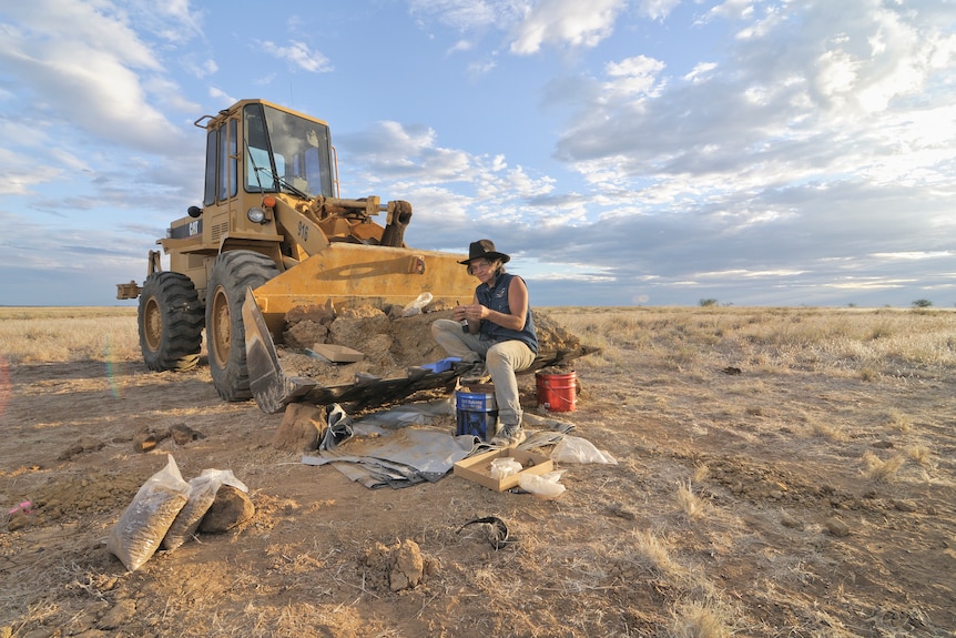 Woman holding small fossil at a dig site in western Queensland.