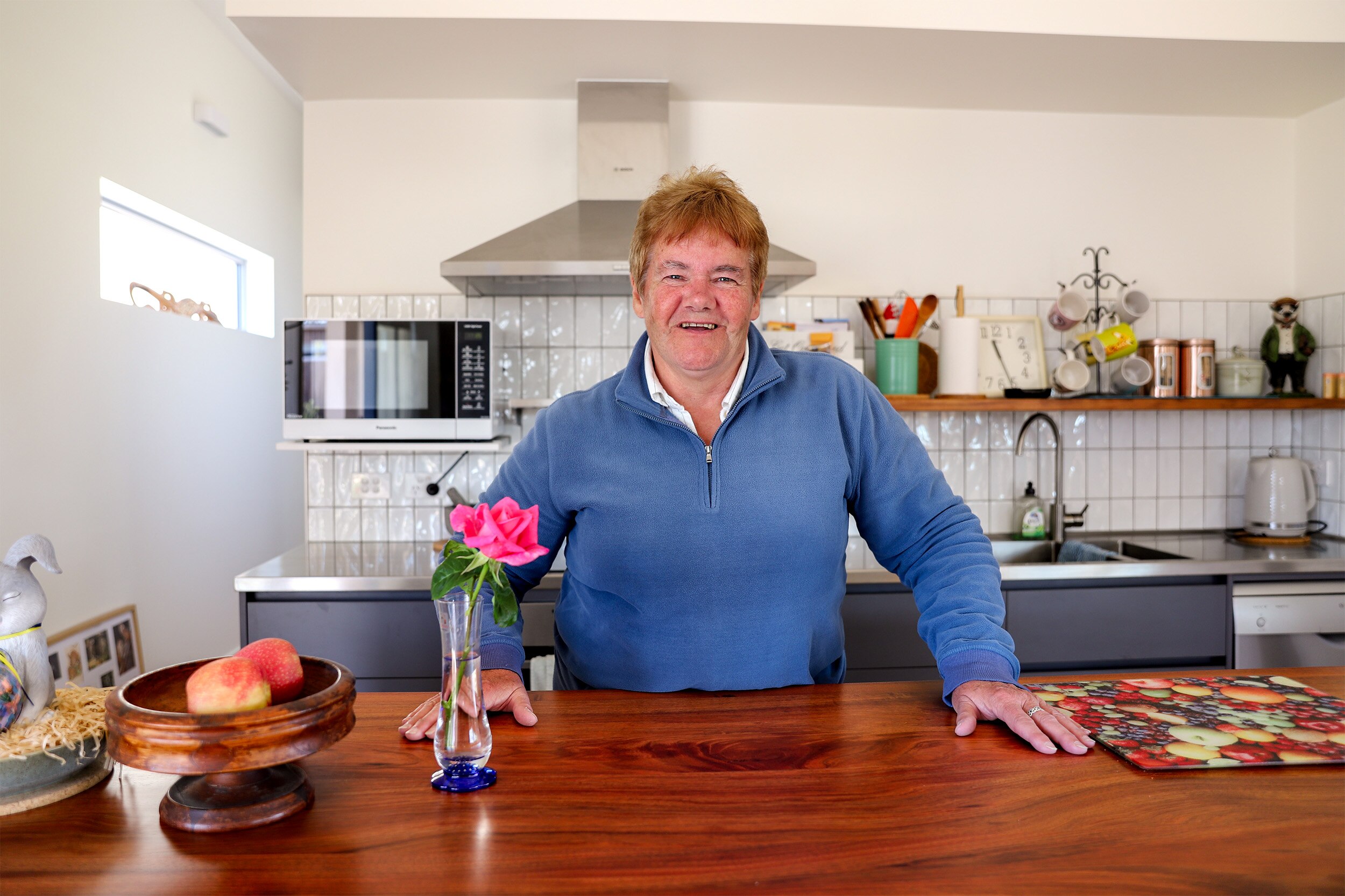 Woman in blue jumper stands at home kitchen counter