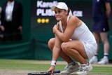 An emotional Ash Barty hunkers down on court as she reacts to the final point of her Wimbledon final win.
