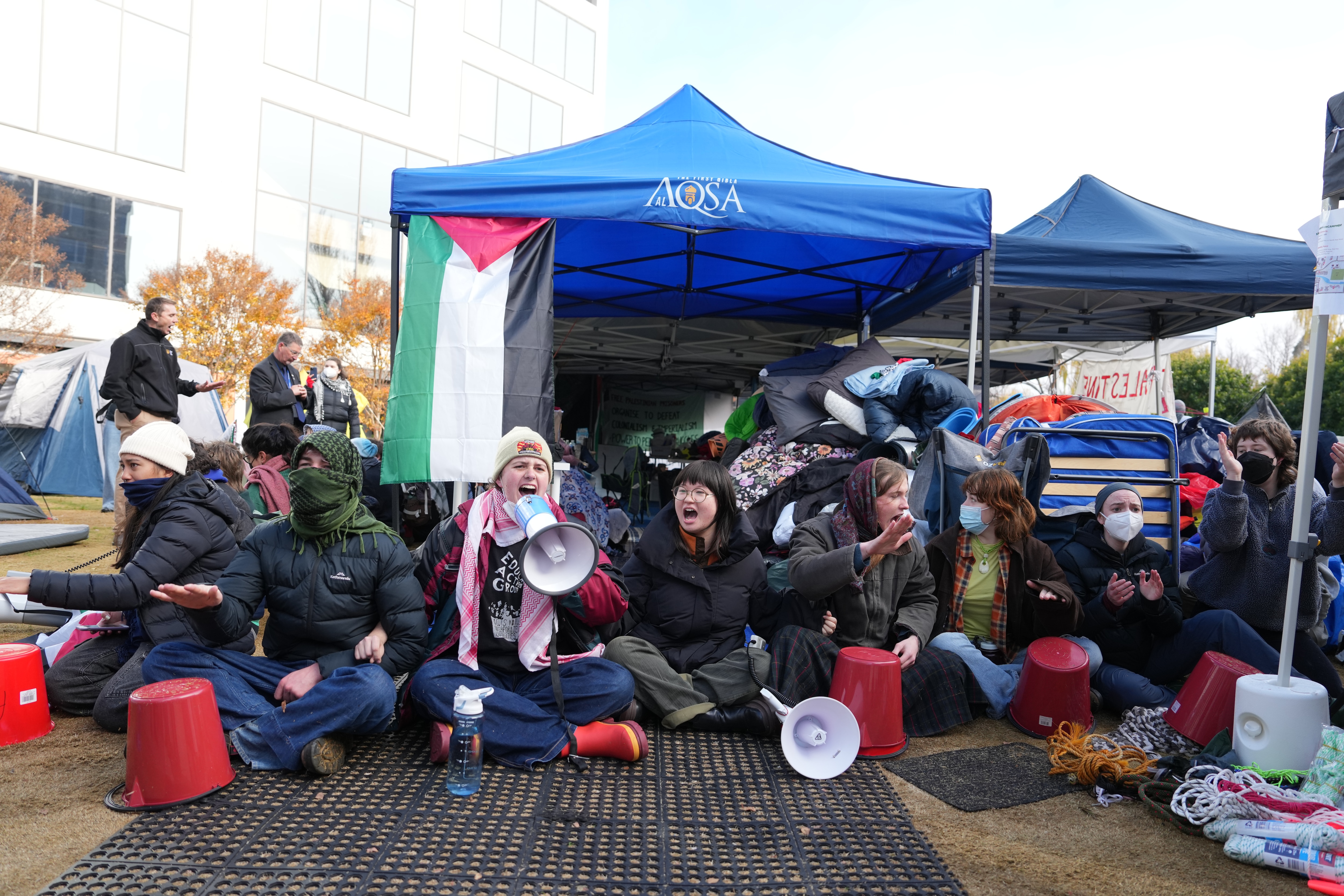 Protesters sit down and chant at the Australian National University pro-Palestine encampment.