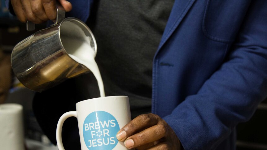 Milk being poured into a 'Brews for Jesus' coffee mug.