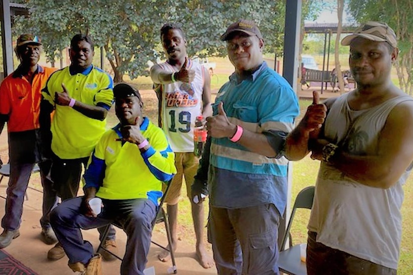 Six men in workwear posing with their thumbs up.