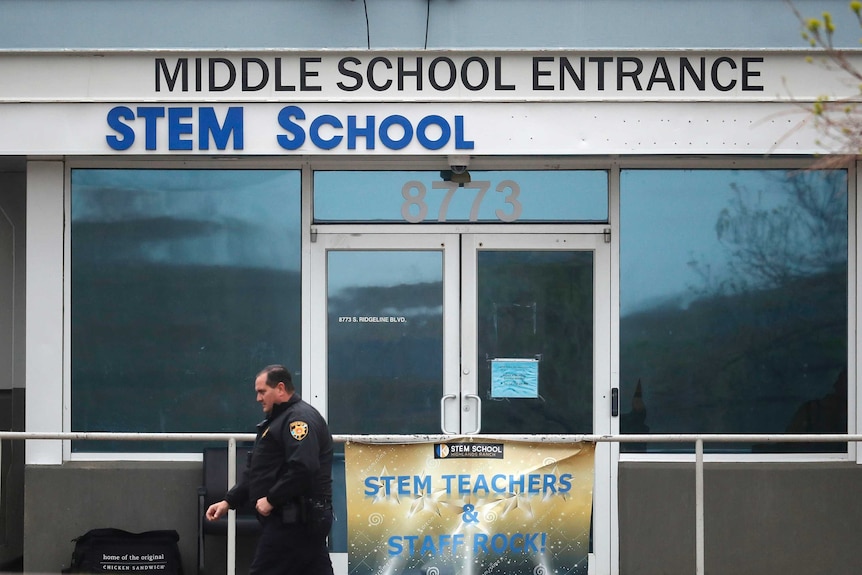 A police officer walks past the doors to STEM Highlands Ranch school in Colorado.