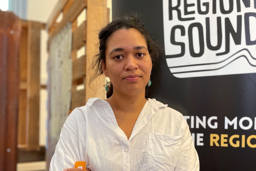 A close shot of a solemn-looking woman in front of a banner reading "Regional Sounds". 