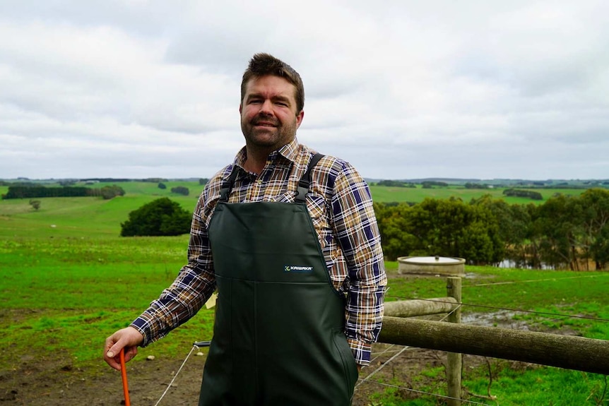 Jason Smith stands besides a fence on his farm.