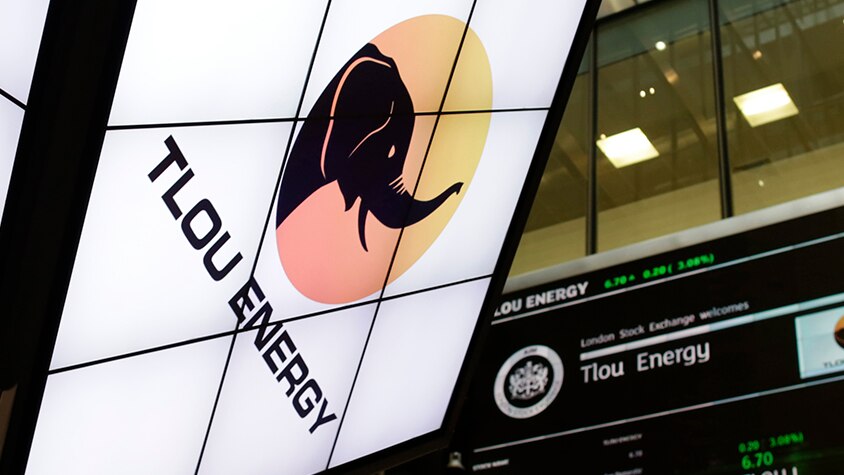 The Tlou Energy logo is displayed on a screen inside a building along with stock price information.
