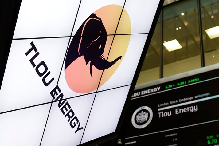 The Tlou Energy logo is displayed on a screen inside a building along with stock price information.