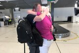 Married couple Jacky and Steve Dennie hug as they reunite at Brisbane airport.