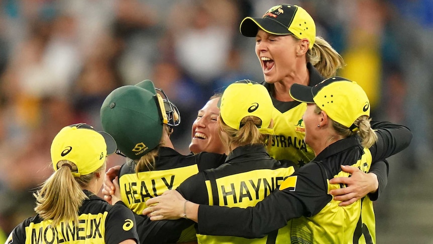 A group of Australian players converge in celebration.