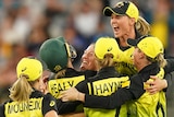 A group of Australian players converge in celebration.