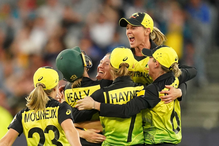 A group of Australian players converge in celebration.