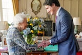 Queen Elizabeth II shakes Justin Trudeau's hand in a room featuring blue and yellow flowers