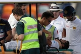 Australia cricketers Tim Paine (second from left) and Pat Cummins (centre) check on Dimuth Karunaratne while he's on a medicab.