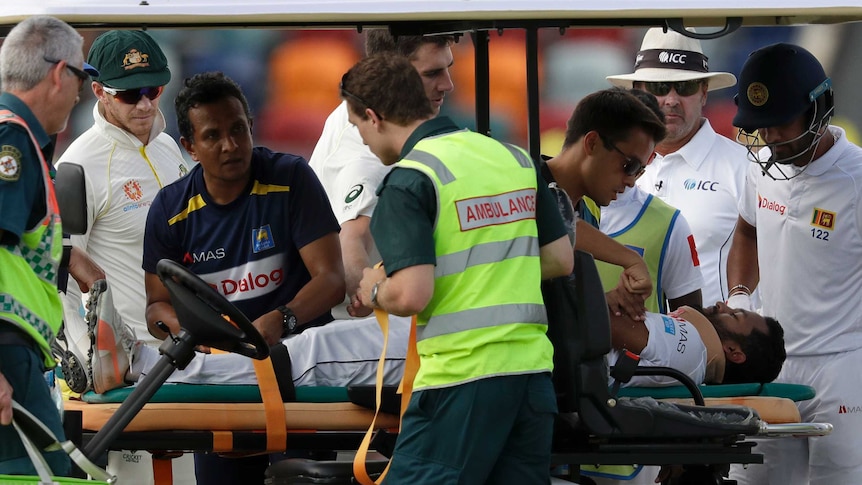 Australia cricketers Tim Paine (second from left) and Pat Cummins (centre) check on Dimuth Karunaratne while he's on a medicab.