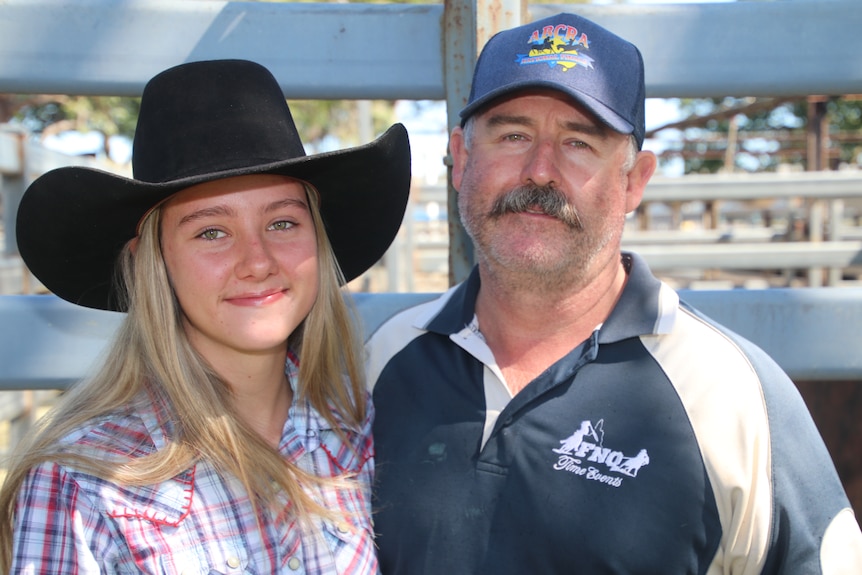 Bonnie in a black hat standing beside her dad who is wearing a blue hat