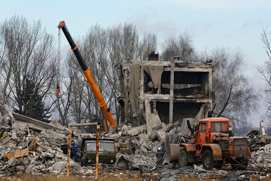 Workers remove debris of a destroyed building in Makiivka, Ukraine.