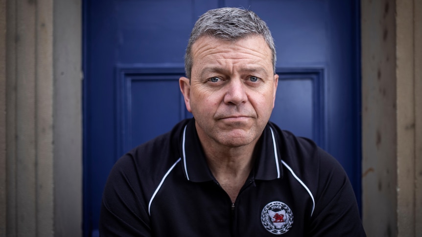 Man sitting in front of a blue door.