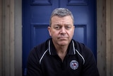 Man sitting in front of a blue door.