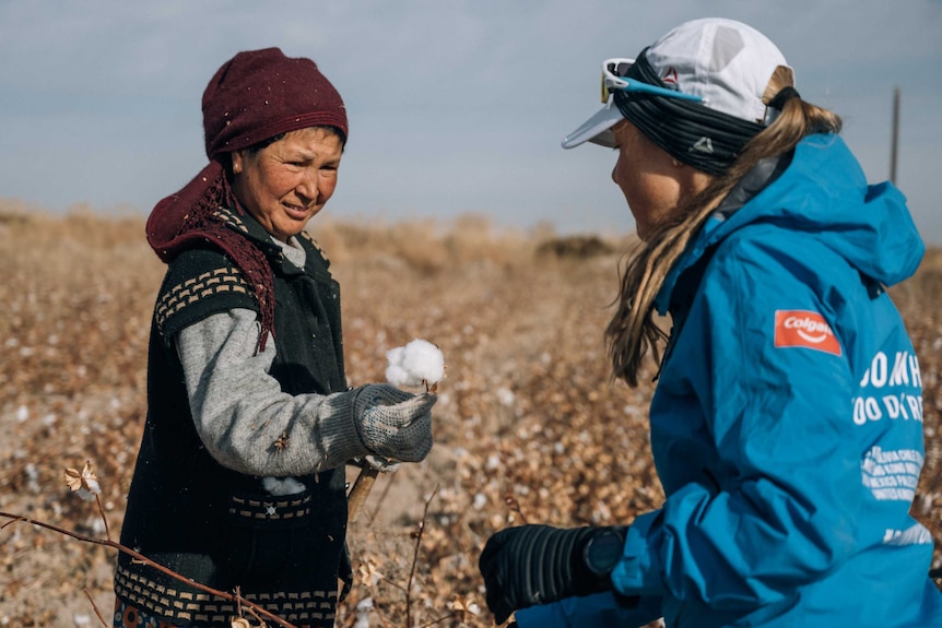 Elderly local Nukus woman showing cotton plant to Mina Guli in the cotton field