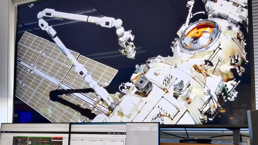 Vision of the  European Robotic Arm in operation at the International Space Station on a big screen in front of computers