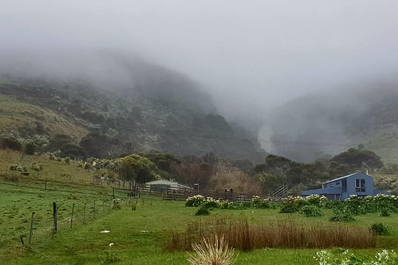 Mist shown among green hills in the background with a farm house in front of the land. Taken at Apollo Bay
