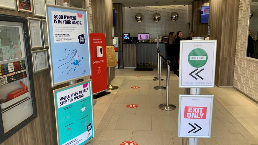 The entrance of the Broken Hill Demo Club with hand sanitising stations &  signs reminding patrons to follow its COVID-19 rules.