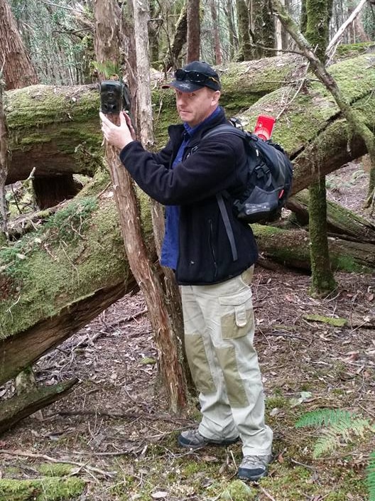 Warren Darragh with a motion sensing camera in the Tasmanian bush.